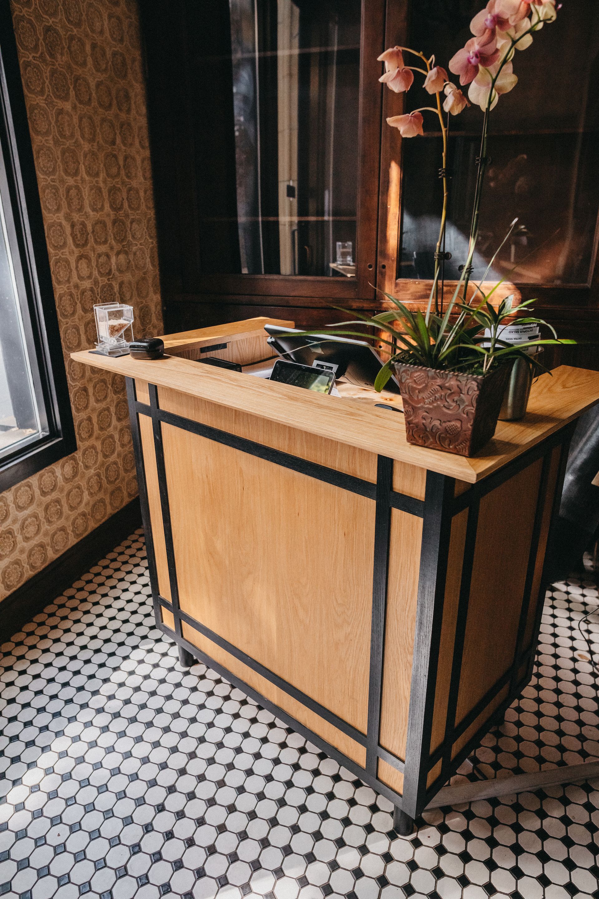 A wooden desk with a potted plant on top of it in a restaurant.