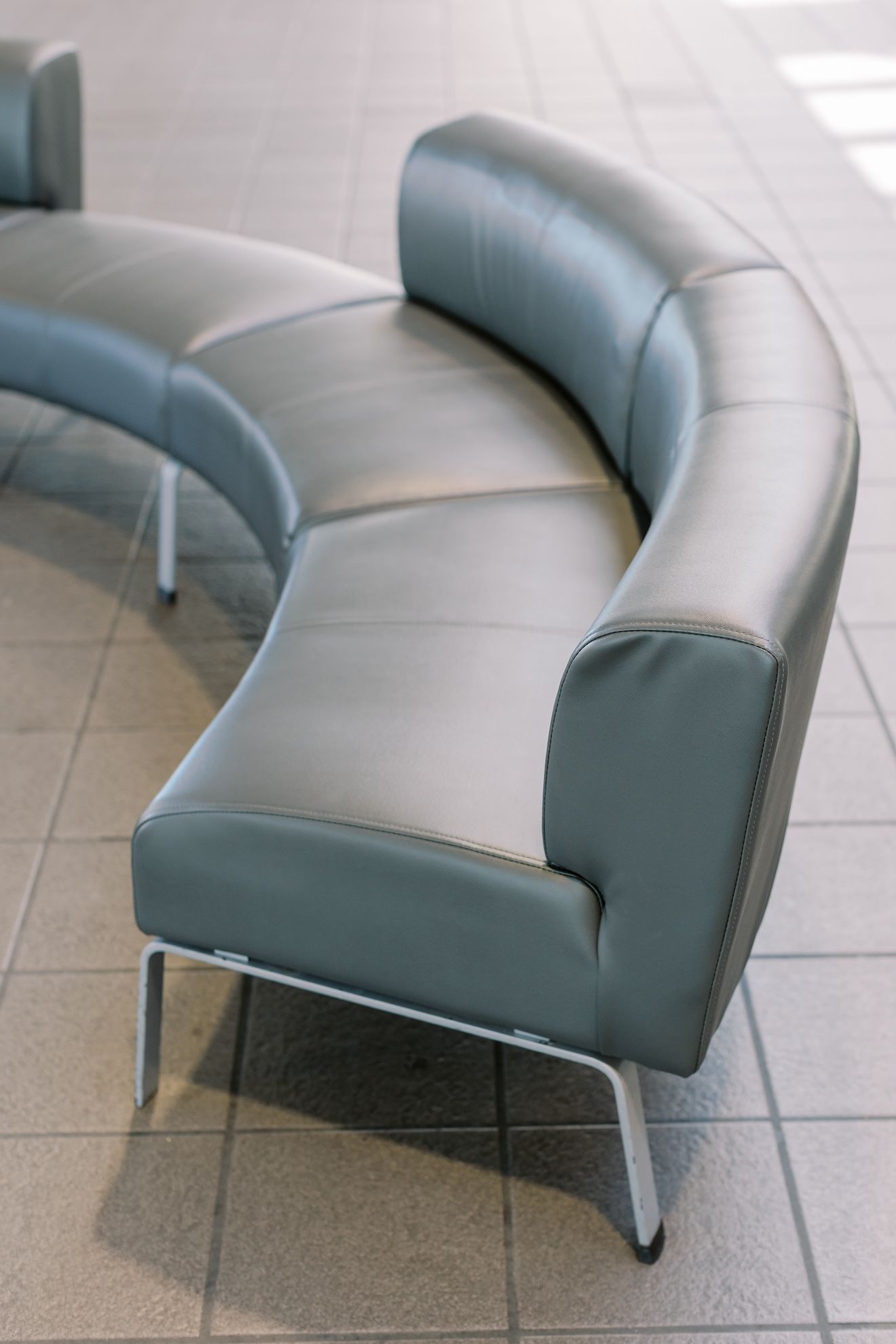 A curved couch is sitting on a tiled floor