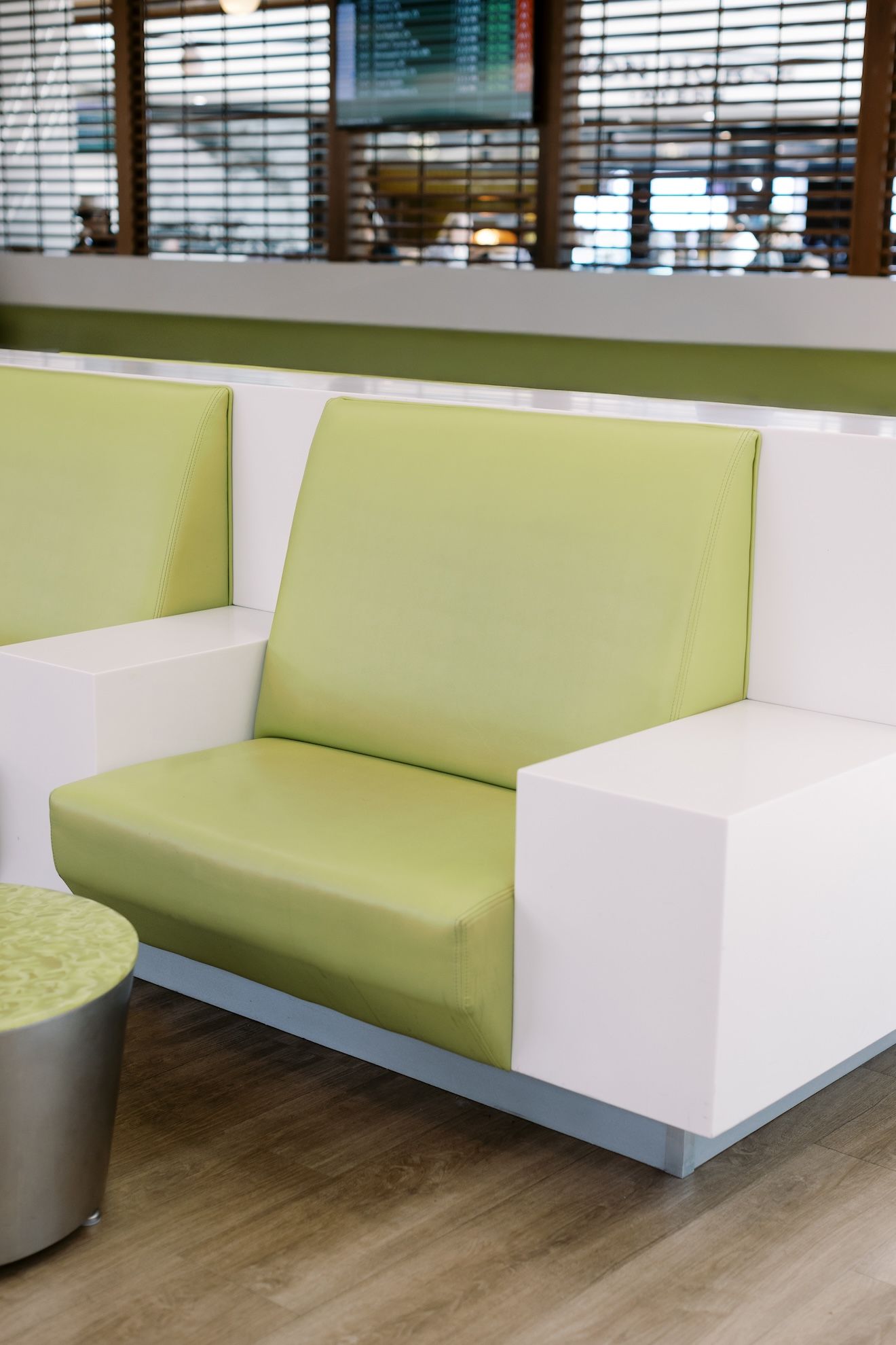 A green and white couch is sitting in a waiting room.