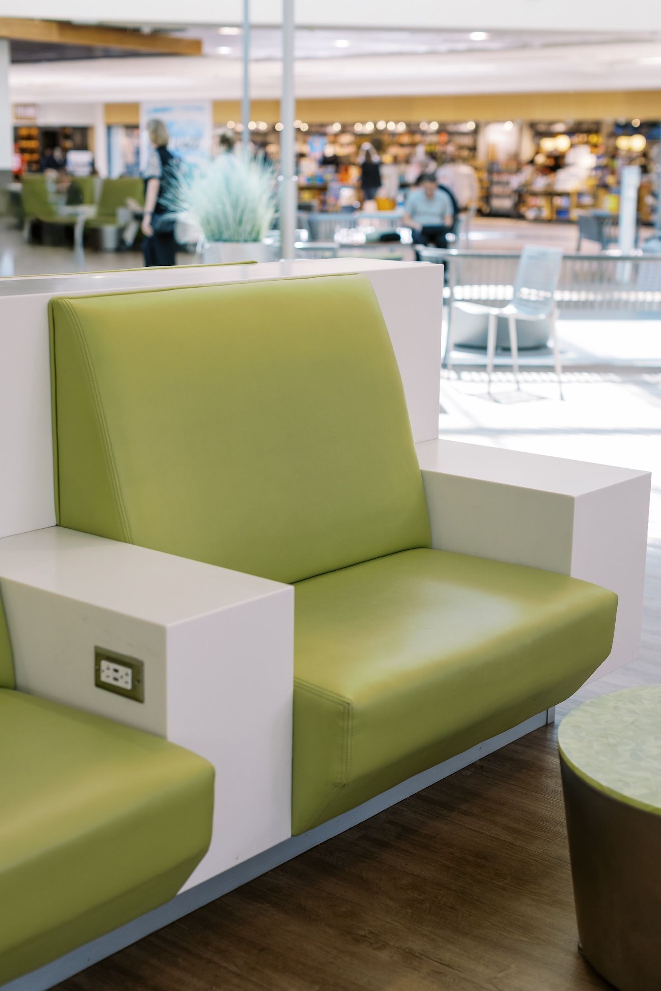 A green chair with a white arm rest is sitting in a waiting room.