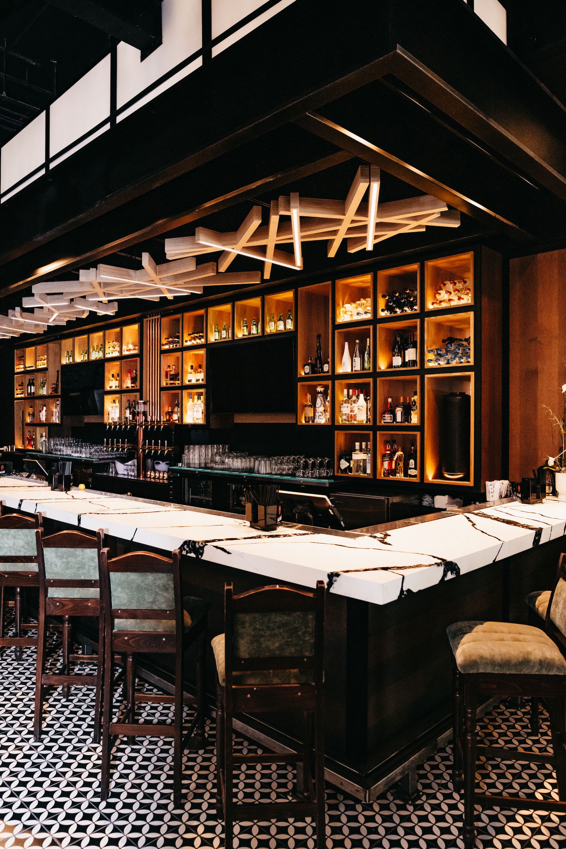 A long bar in a restaurant with a lot of bottles on the shelves.