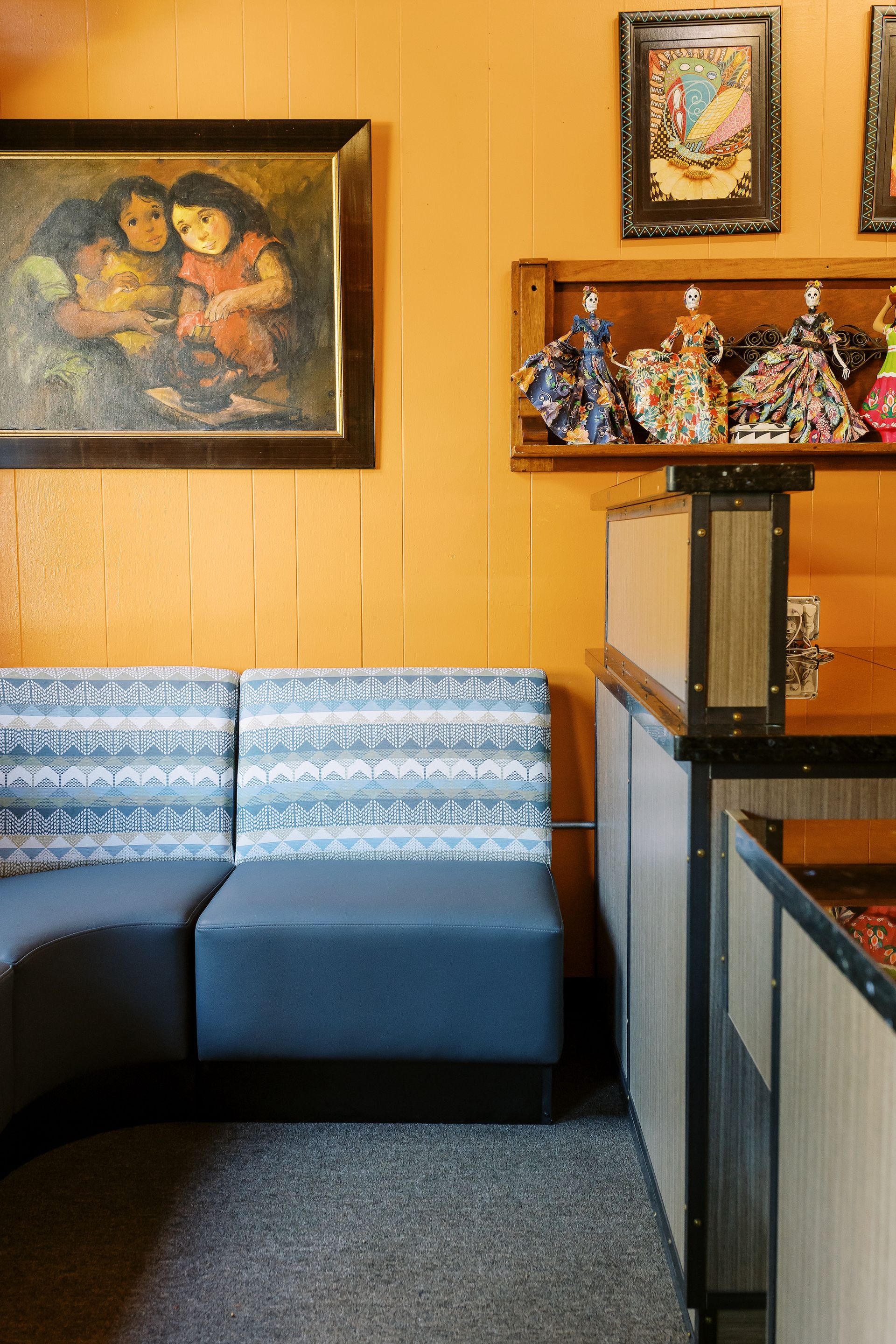 A restaurant with a couch and a painting on the wall.