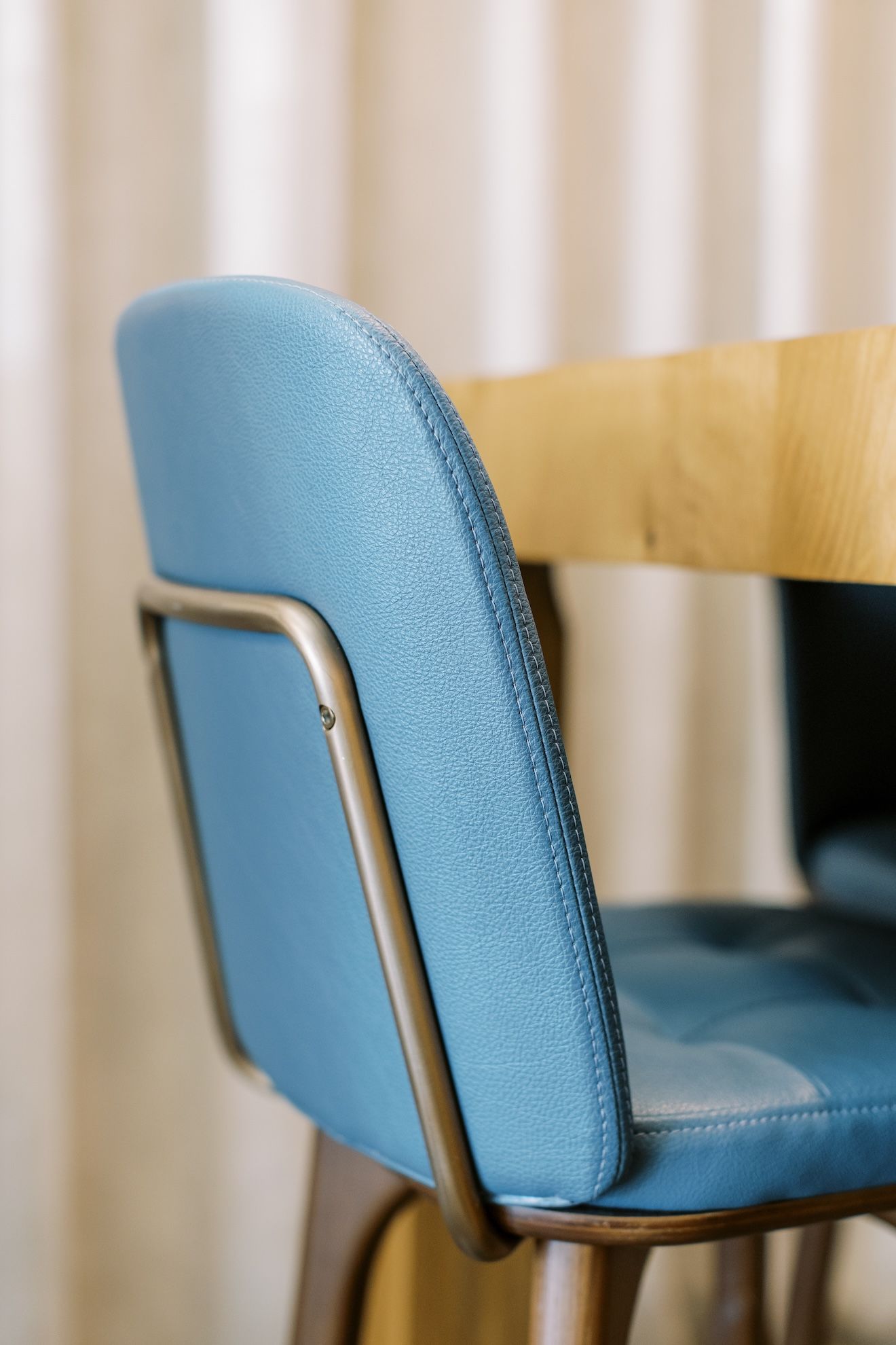 A close up of a blue chair with a wooden table in the background.