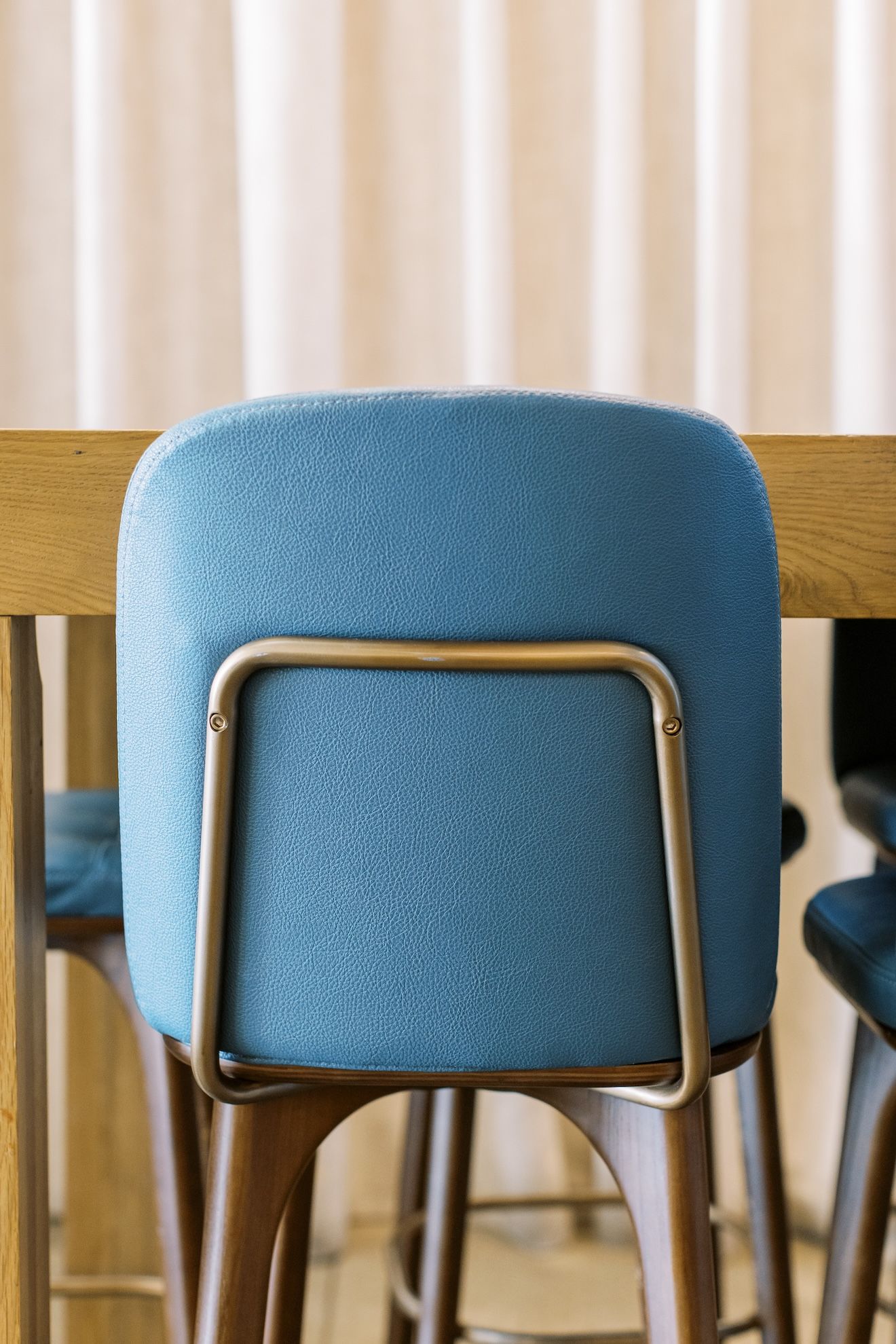 A blue chair is sitting next to a wooden table.