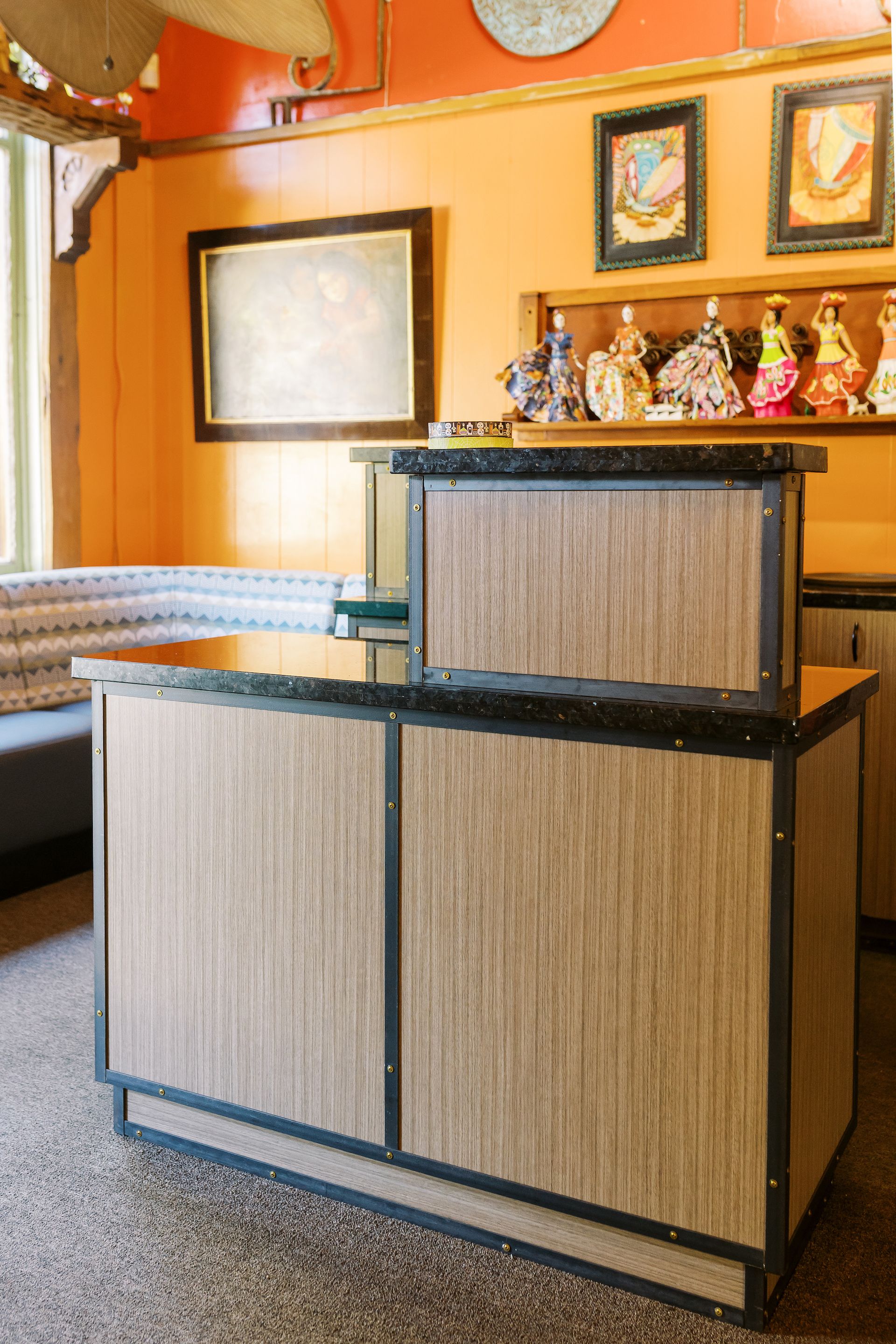 A wooden counter in a room with a shelf with figurines on it.