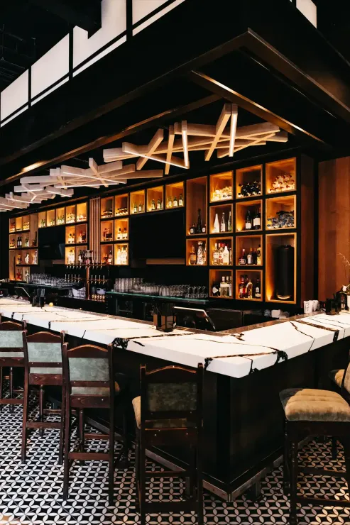 A long bar in a restaurant with a lot of bottles on it
