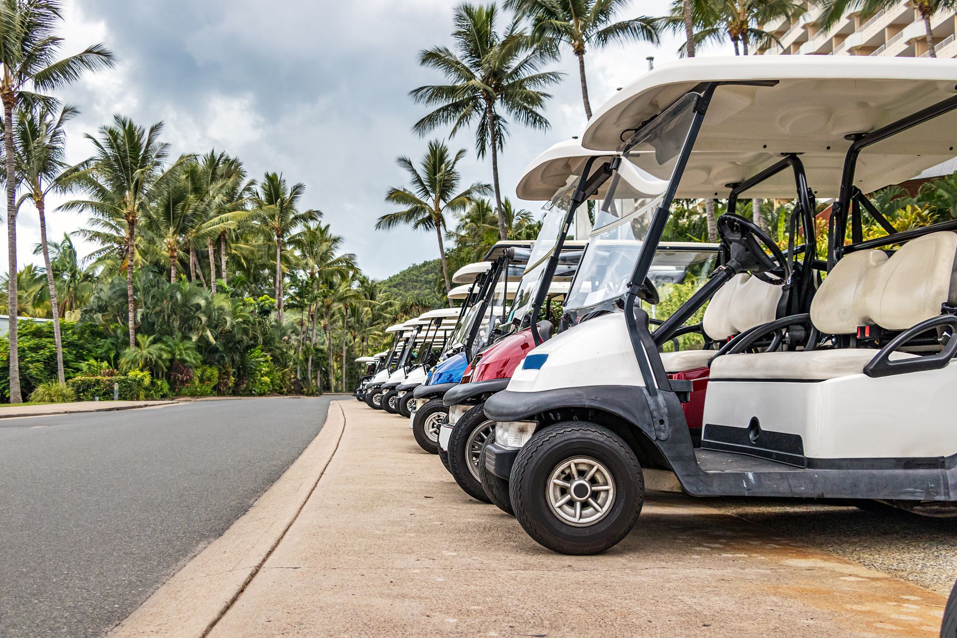 A row of golf carts parked on the side of the road.