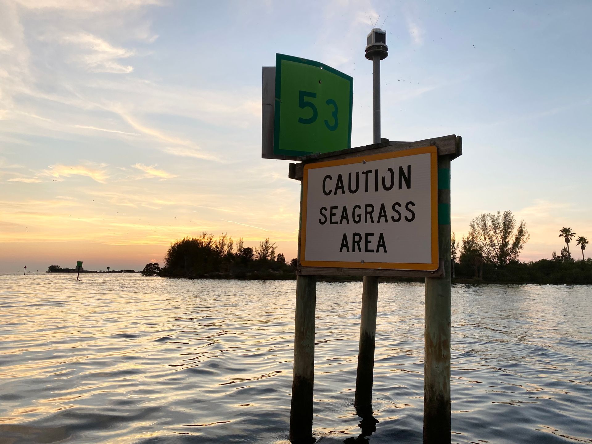 A sign in the water says caution seagrass area