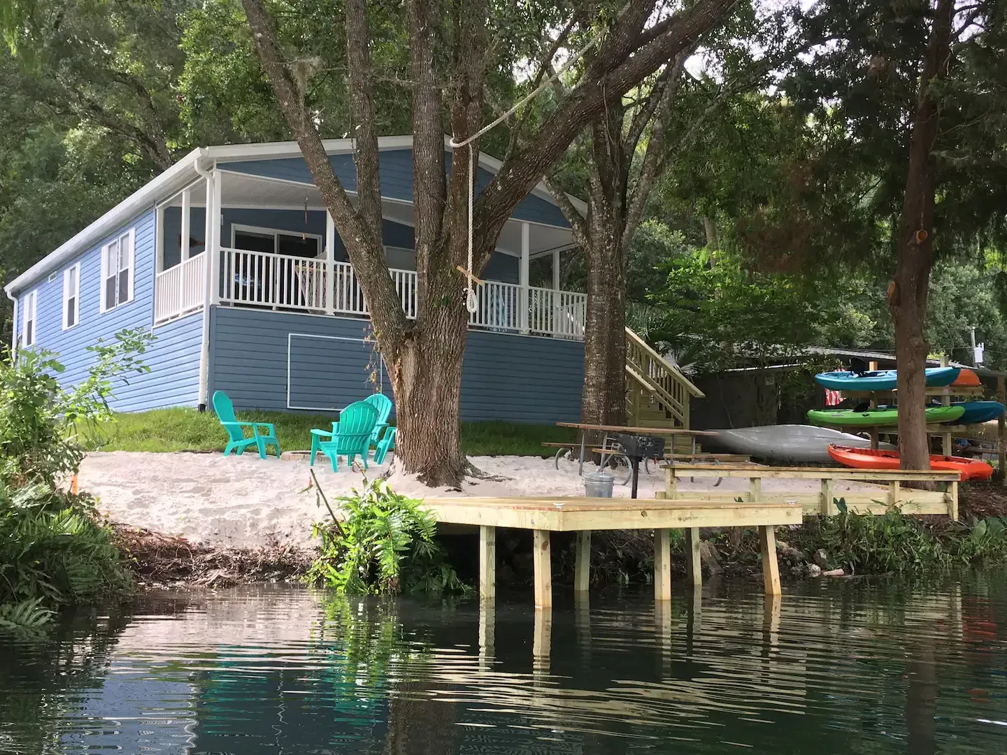 A blue house with a dock next to a body of water.