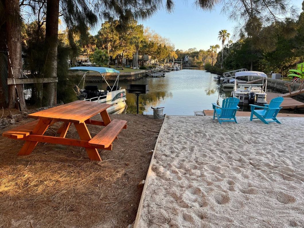 A picnic table and chairs on a sandy beach next to a river.