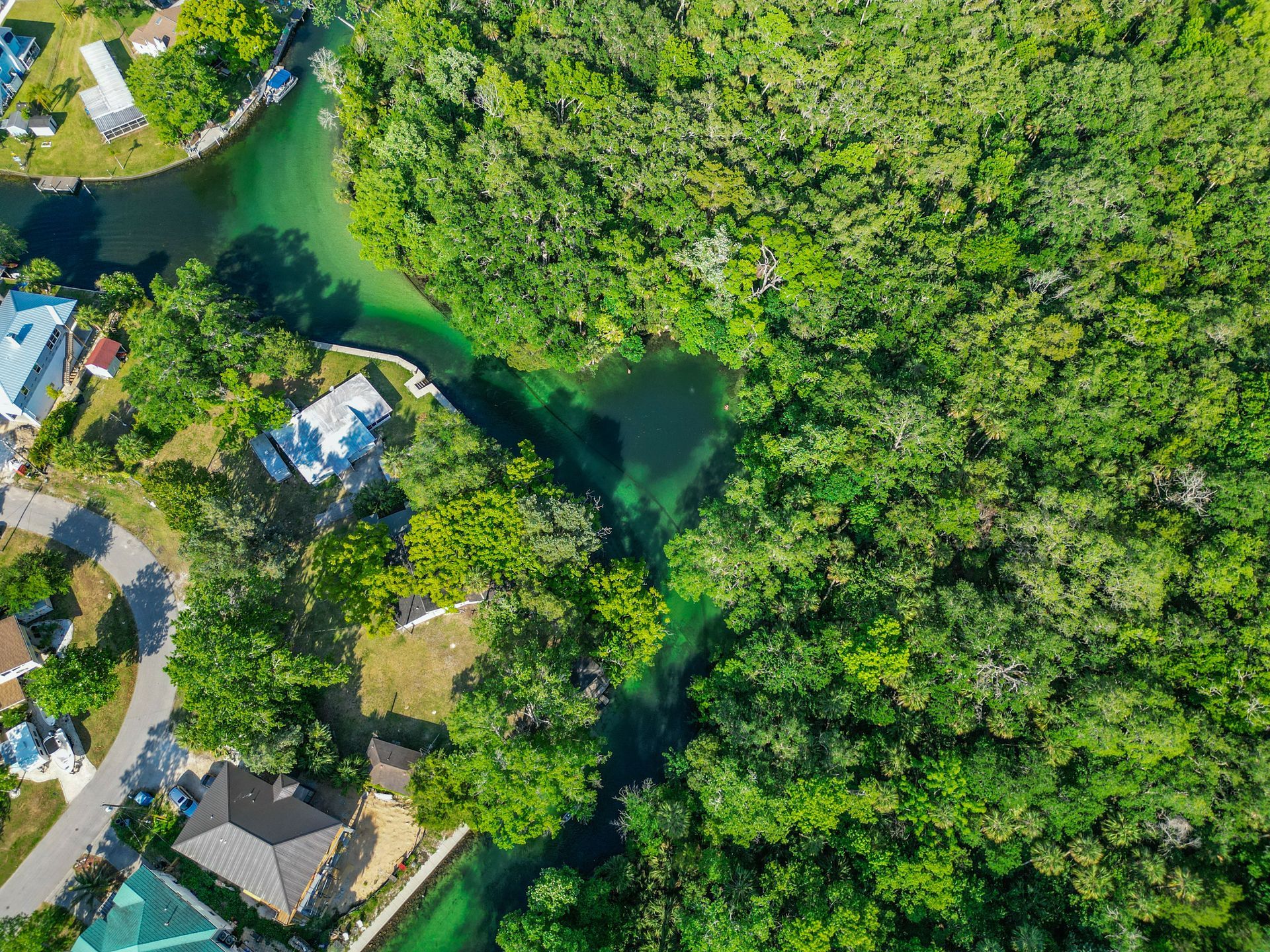 An aerial view of a river running through a residential area surrounded by trees.