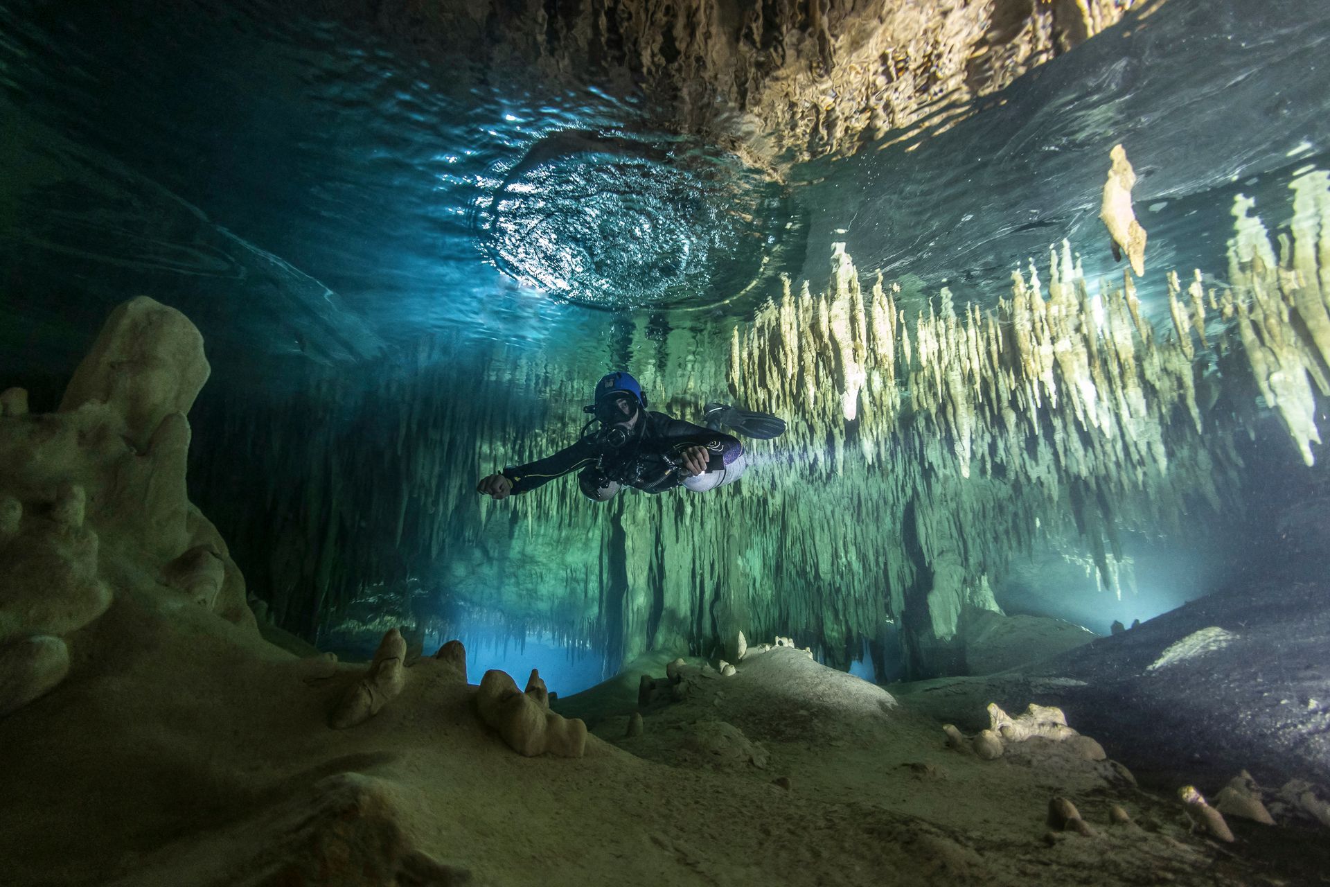 A man is swimming underwater in a cave.