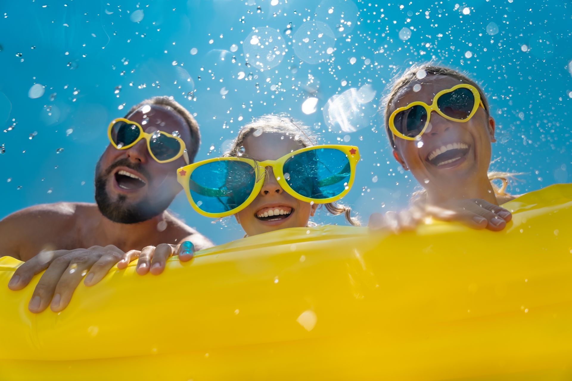 A boy and a girl are playing on a water slide in a swimming pool.