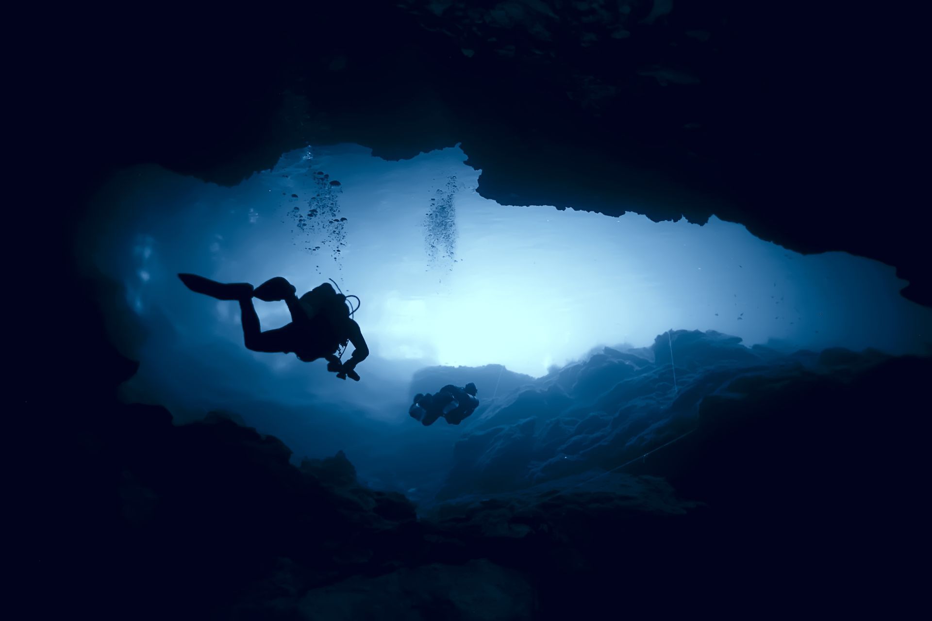 A scuba diver is swimming through a cave in the ocean.