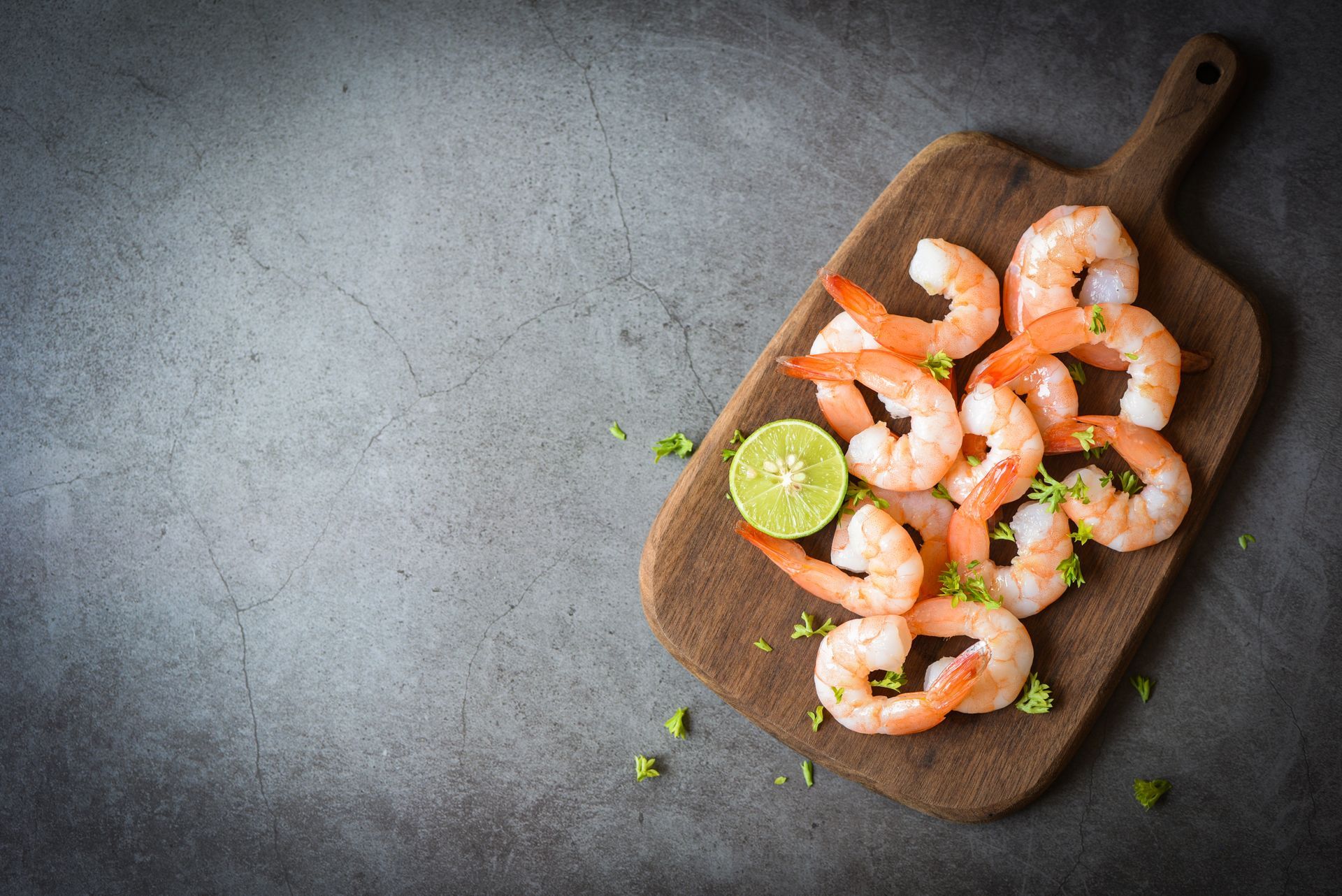 Shrimp on a wooden cutting board with a lime slice.