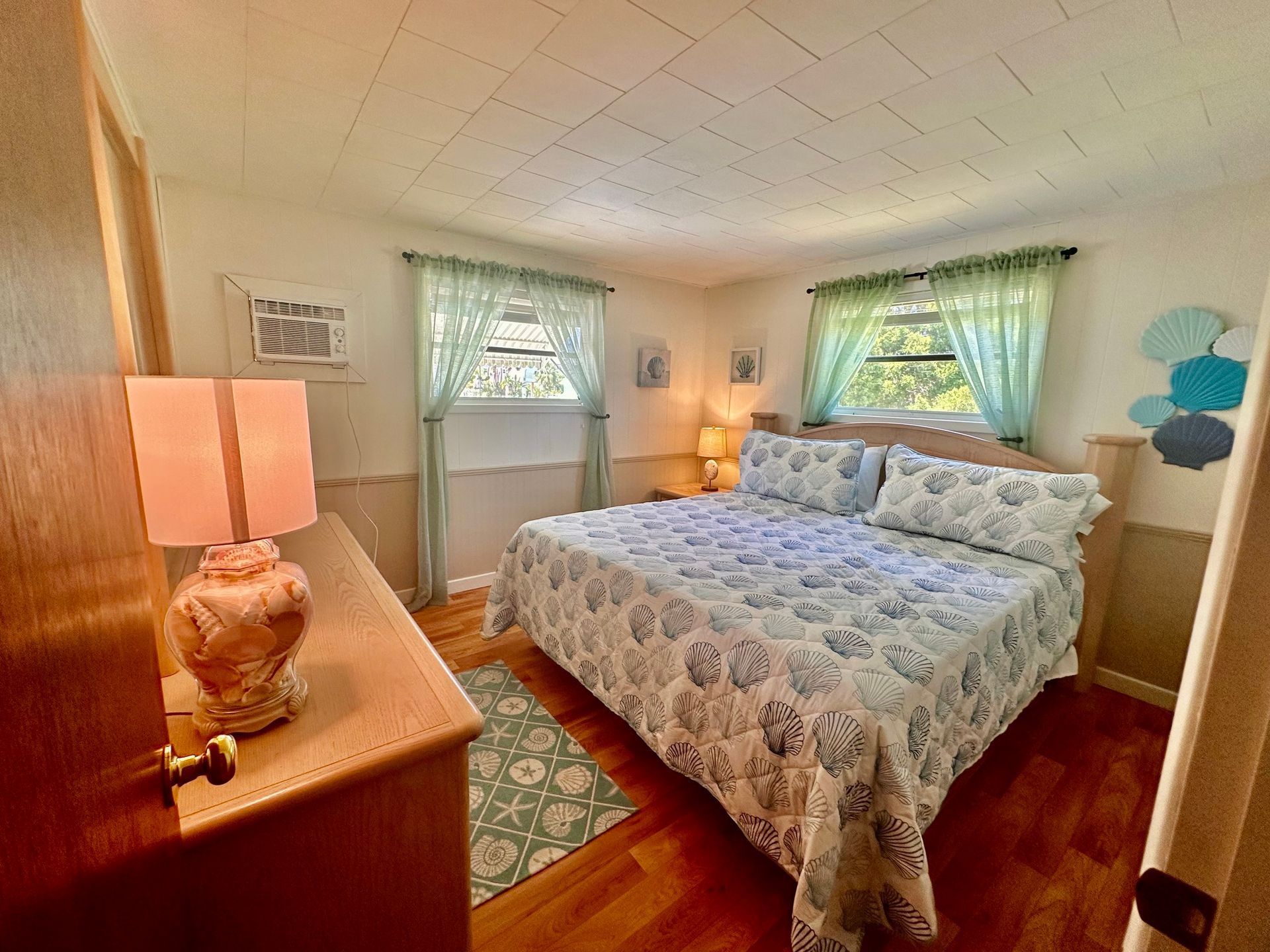 A bedroom with a king size bed , dresser , lamp and window.