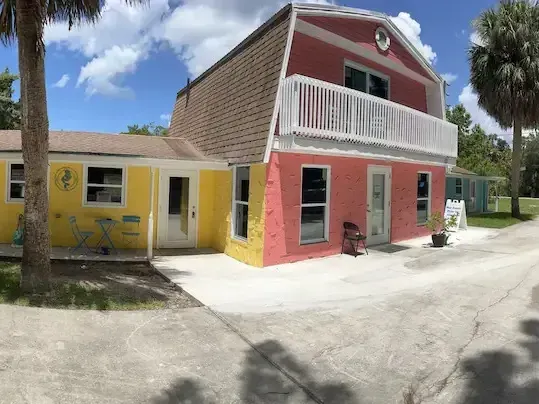 A red and yellow house with a balcony on the second floor.