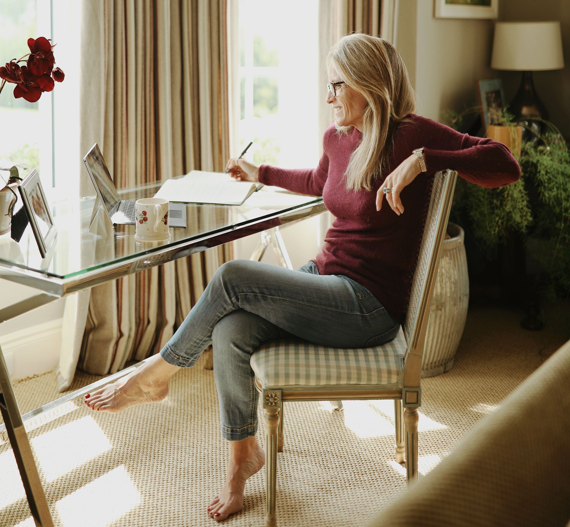 A woman is sitting at a desk writing on a piece of paper