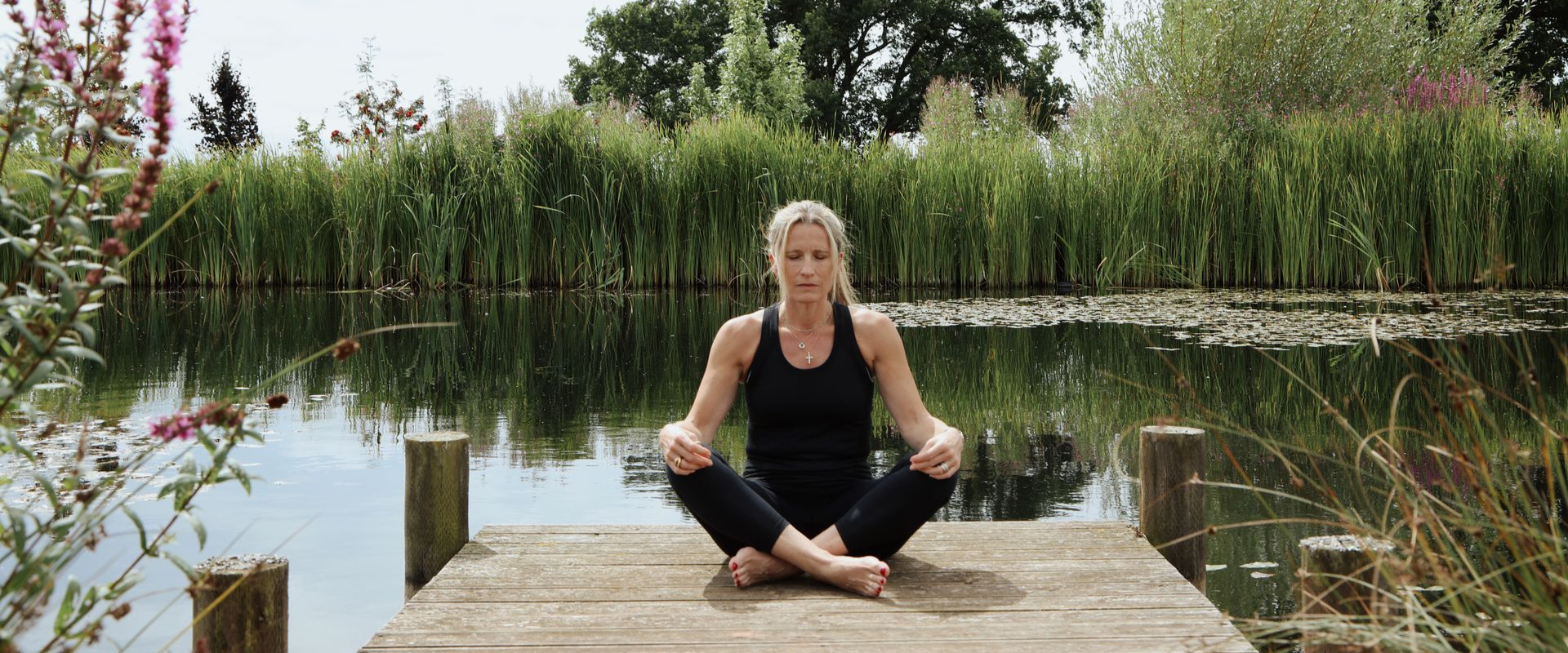 Woman meditating in a peaceful natural setting during a Vipassana retreat.
