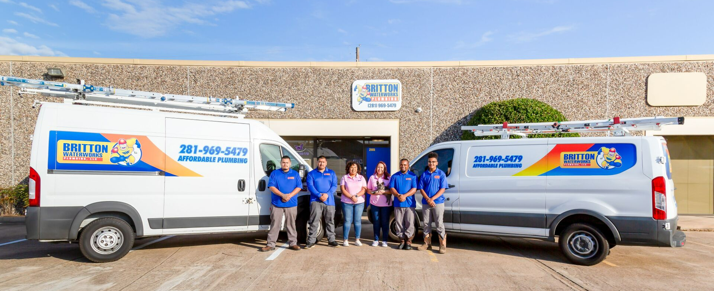 A group of five employees stand between two white work vans labeled 
