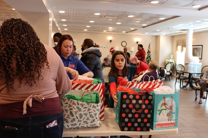 Volunteers organize and pack gift bags on tables inside a community room.