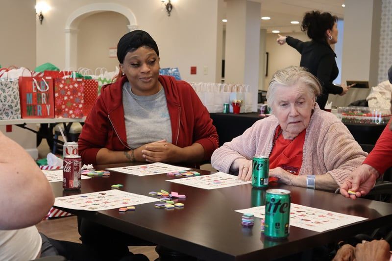 People playing bingo at a table with drinks and gift bags in a community room.