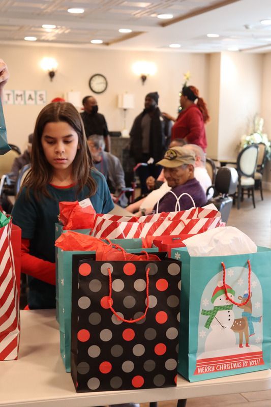 A person sets out gift bags on a table at a gathering, with other people standing in the background.