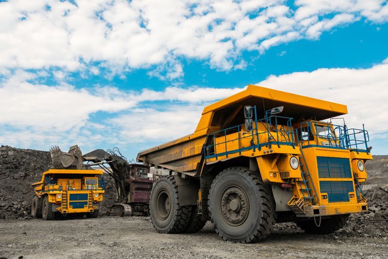 Two yellow dump trucks are parked next to each other in a dirt field — Hydro Excavation in Narellan, NSW