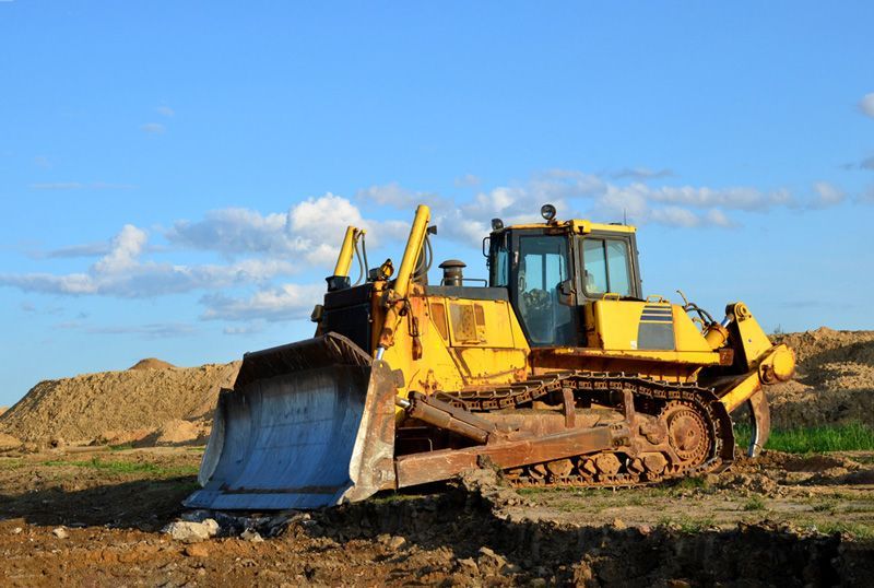 A yellow bulldozer is sitting on top of a dirt field — Hydro Excavation in Bowral, NSW