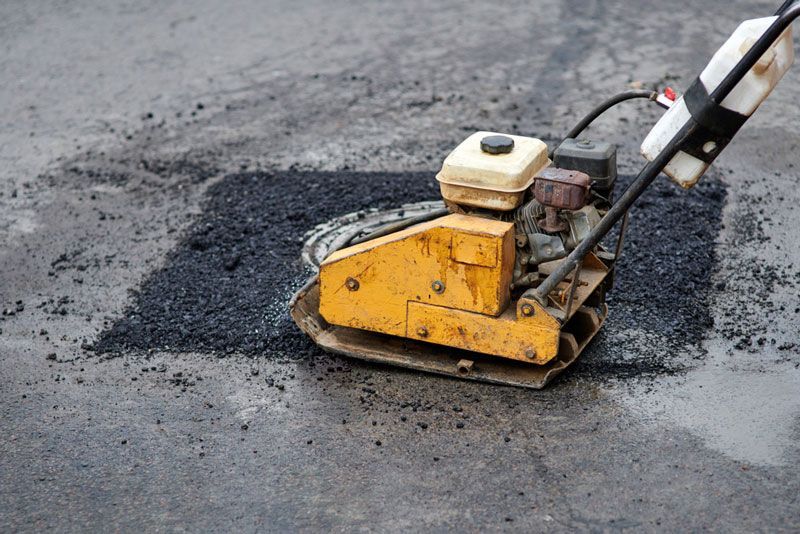 A yellow machine is laying asphalt on the ground — Hydro Excavation in Moss Vale, NSW