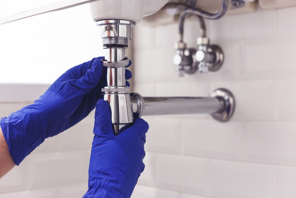 A plumber is fixing a sink pipe in a bathroom — Hydro Excavation in Queanbeyan, NSW