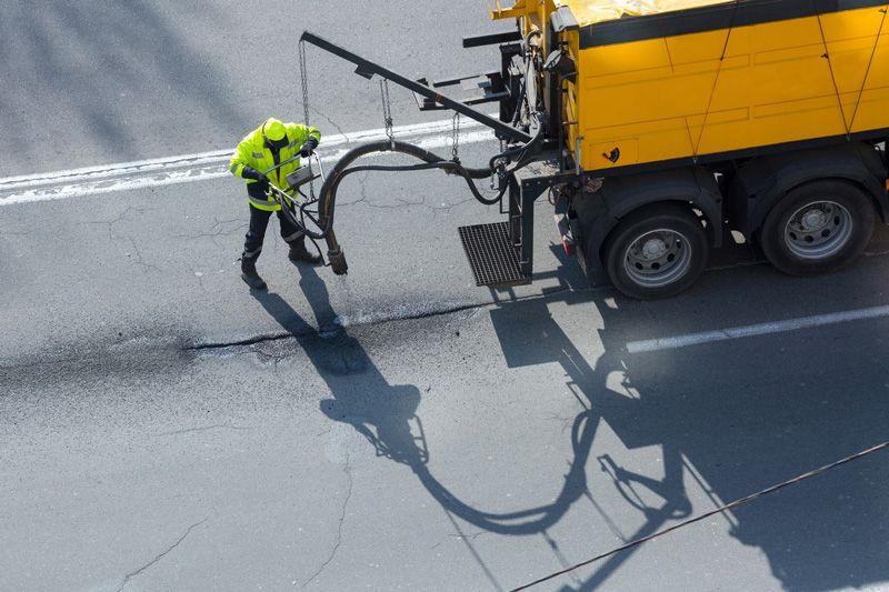 A man in a yellow vest is standing next to a yellow truck — Hydro Excavation in Mittagong, NSW