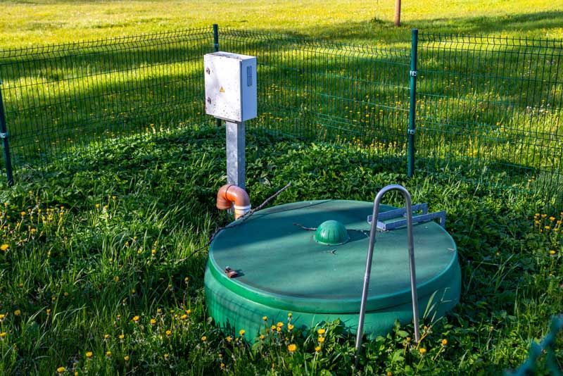 A green septic tank is sitting in the middle of a grassy field — Hydro Excavation in Bowral, NSW