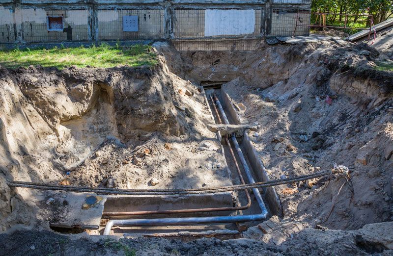 A large hole in the ground with pipes coming out of it — Hydro Excavation in Bowral, NSW