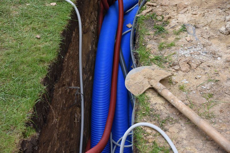 A blue pipe is being installed in a trench next to a shovel — Hydro Excavation in Camden, NSW