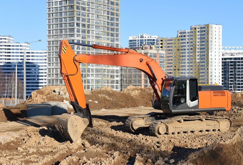 A large orange excavator is digging a hole at a construction site — Hydro Excavation in Yass, NSW