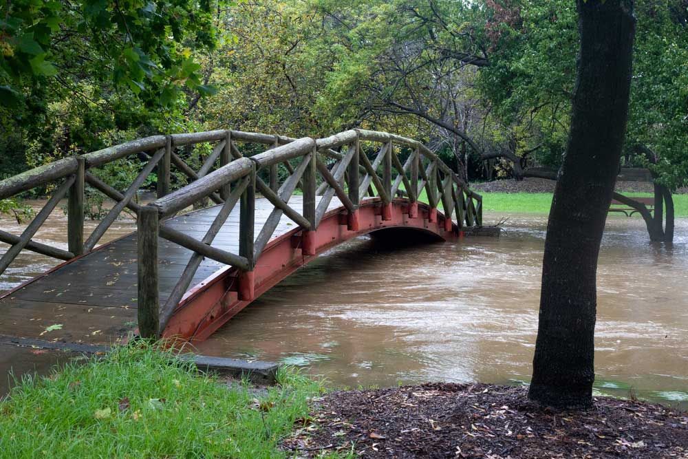 A wooden bridge over a flooded river in a park — Hydro Excavation in Mittagong, NSW