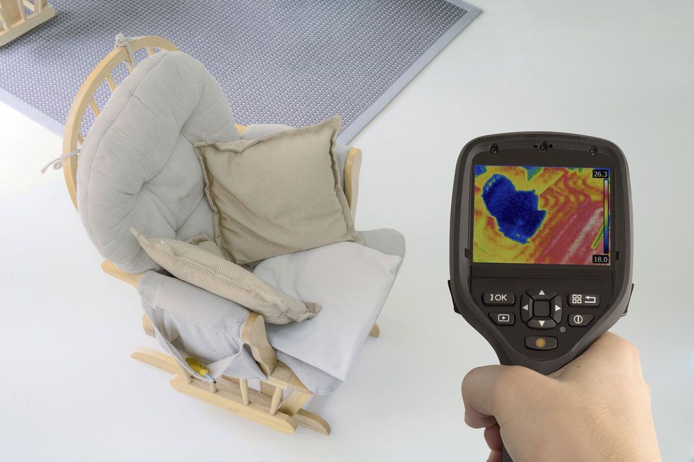 A person is holding a thermal camera next to a rocking chair — Hydro Excavation in Camden, NSW
