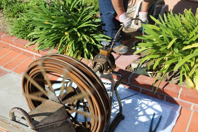 A person is using a drain cleaner on a brick sidewalk — Hydro Excavation in Goulburn, NSW