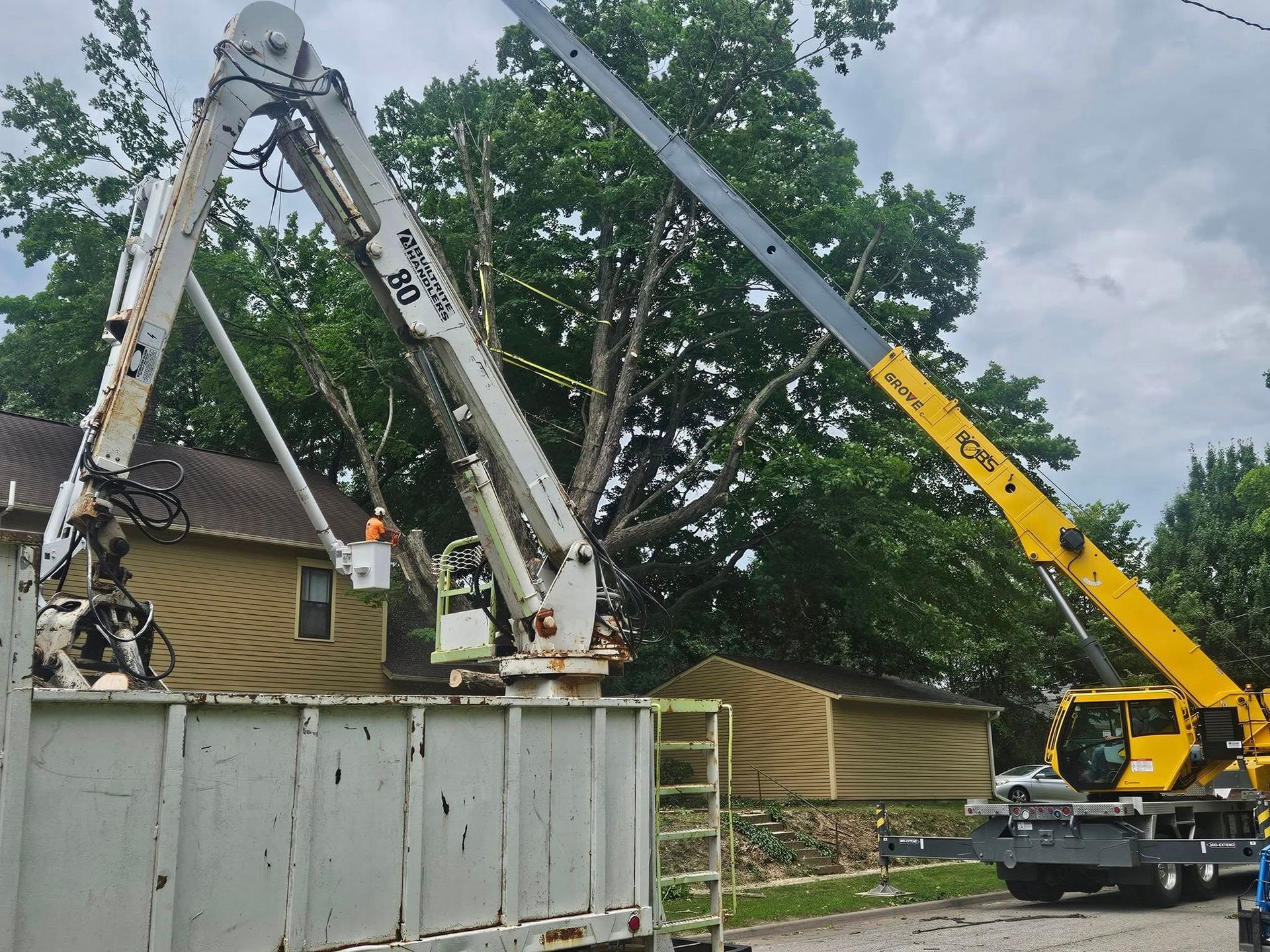 Two cranes lifting a large concrete container in a yard under cloudy skies