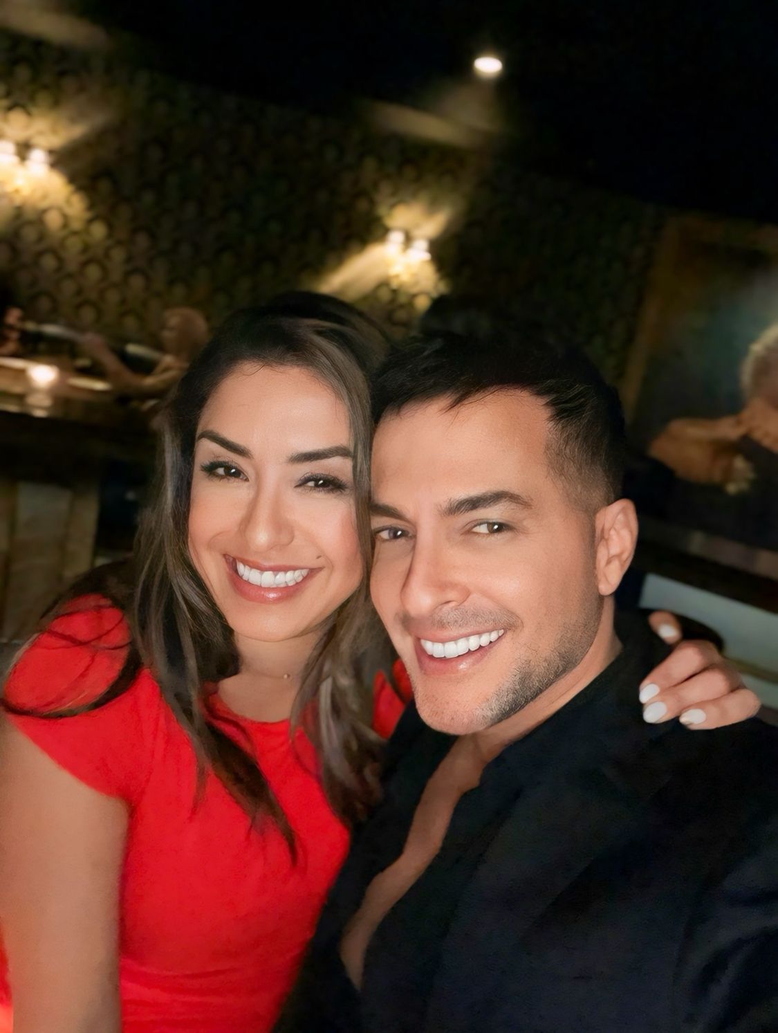 A man and a woman are posing for a picture together and smiling.
