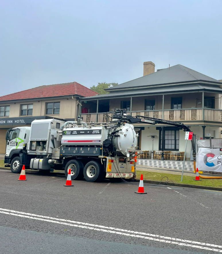 A Vacuum Truck Is Parked On The Side Of The Road In Front Of A House — East Coast Locating Services In Port Stephens, NSW