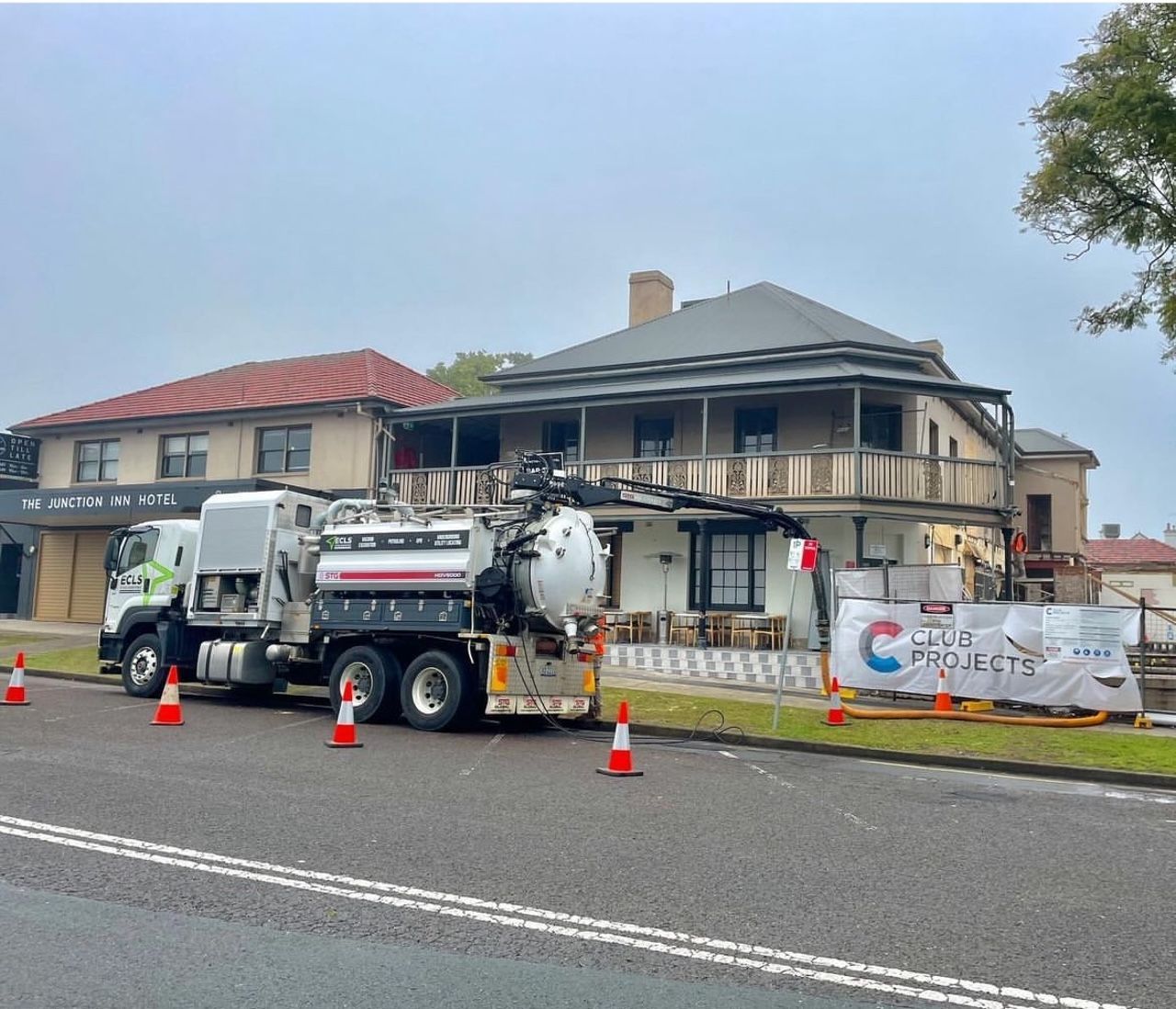 A vacuum truck is parked on the side of the road in front of a house.