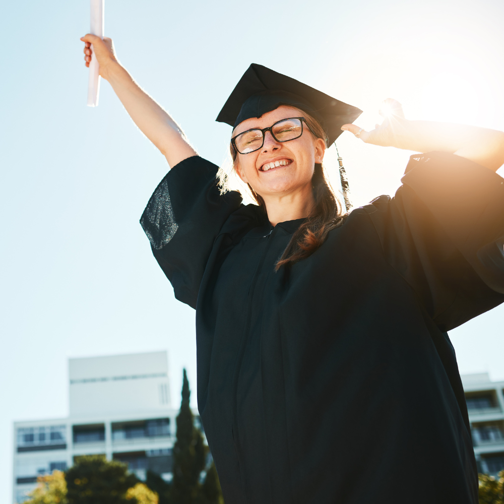 A woman in a graduation cap and gown is holding a diploma in her hand.