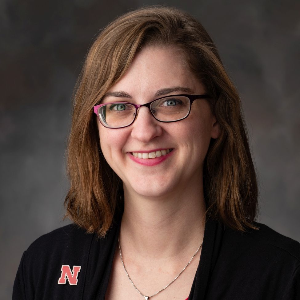 A woman wearing glasses and a black shirt with the letter n on it.