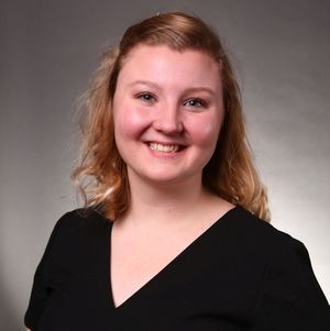 The woman is wearing a black shirt and smiling for the camera.