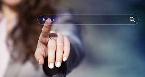 A woman is pointing at a search bar on a computer screen.