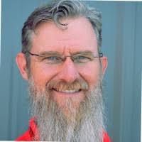 A man with a long beard and glasses is smiling for the camera.