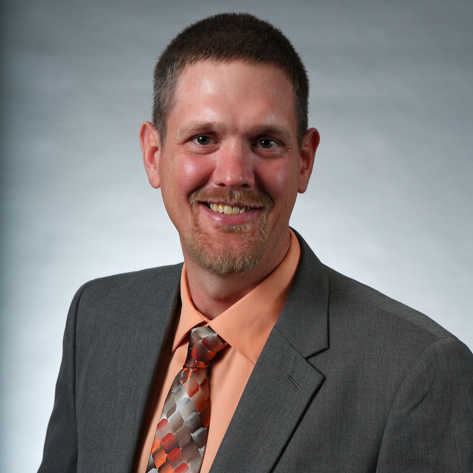 A man in a suit and tie is smiling for the camera