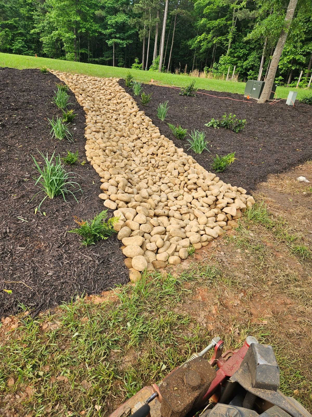 A path made of rocks is going through a lush green field.